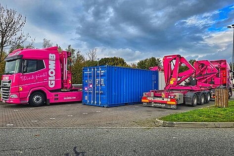 Pinkfarbener Glomb Lkw mit Container auf Parkplatz