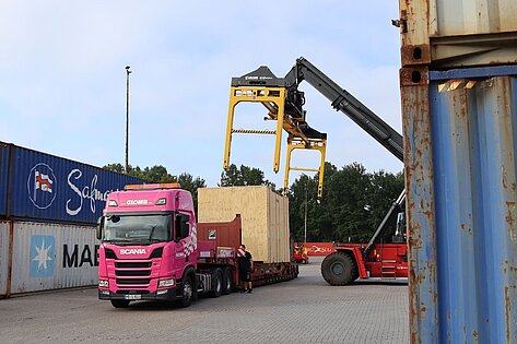 Pinkfarbener Glomb Lkw mit Sonderladung im Terminal