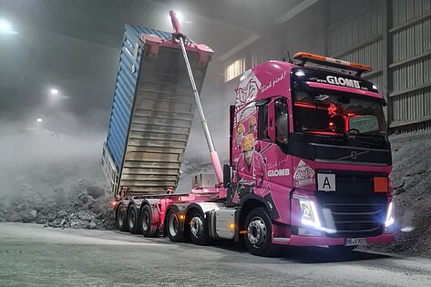 Pink GCD Glomb truck unloading a container.